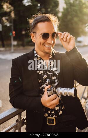 Jeune photographe homme prendre des photos sur l'appareil photo de beau coucher de soleil et chapeau prendre des photos avec l'appareil photo vintage Banque D'Images