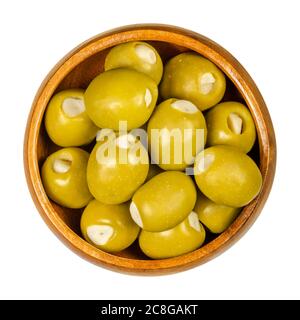 Olives vertes farcies aux gousses d'ail dans un bol en bois. Grandes olives, fruits d'Olea europaea, fourrées à la main de morceaux d'ail marinés. Gros plan. Banque D'Images