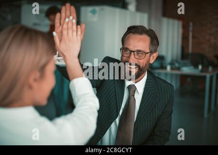 Cinq gestes de la part des professionnels au bureau. Heureux homme caucasien et femme blonde se tiennent avec les mains jointes dans le geste joyeux. Célébration de Banque D'Images