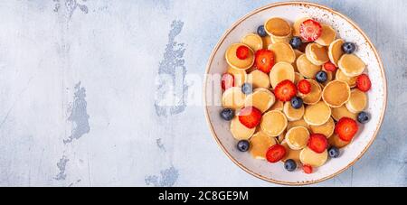 Petites crêpes avec fraises et bleuets pour le petit déjeuner. Vue de dessus. Banque D'Images