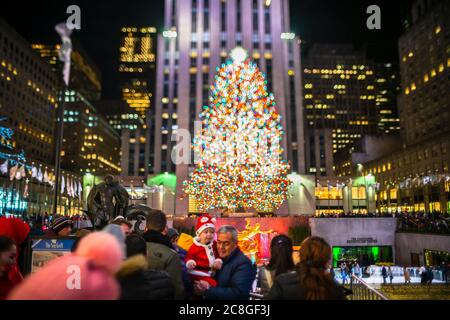 Un grand arbre de Noël se illumine au milieu des bâtiments du Rockefeller Center Banque D'Images