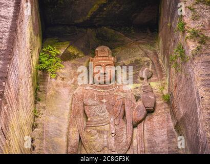 chiba, japon - juillet 18 2020 : gros plan sur l'image de relief géant du bouddha japonais hyaku-shaku kannon sculpté dans la cavité de mur de pierre excavée couverte de wi Banque D'Images