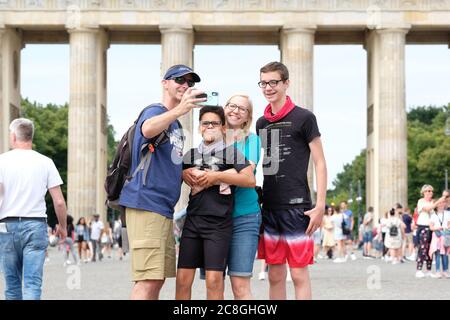 Berlin, Allemagne - vendredi 24 juillet 2020 - les touristes reviennent à Berlin pendant la crise du coronavirus - avec de faibles taux d'infection en ce moment en Allemagne certains voyageurs apprécient la chance de voyager et de visiter les attractions à Berlin beaucoup sans masques faciaux - un groupe de visiteurs posent pour selfie Photos en face de la porte de Brandebourg, Berlin - photo Steven May / Alay Live News Banque D'Images