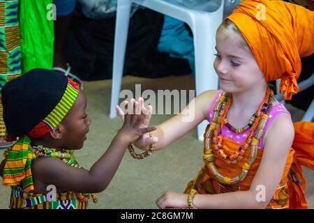 Les filles africaines et blanches (caucasiennes) assises ensemble en regardant les unes les autres et en se touchant les mains Banque D'Images