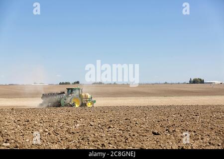 Un agriculteur utilisant un tracteur et un outil de plantation plante des pommes de terre dans les champs fertiles de l'Idaho. Banque D'Images