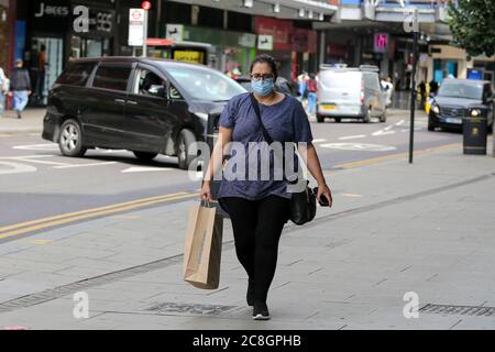 Un acheteur portant un masque facial comme mesure préventive tient un sac de shopping Primark à Londres. Banque D'Images