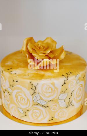 Gâteau de mariage élégant avec une grande rose à glaçage royal dessus couperé de peinture comestible dorée et entouré de fleurs imprimé aquarelle sur fondant Banque D'Images