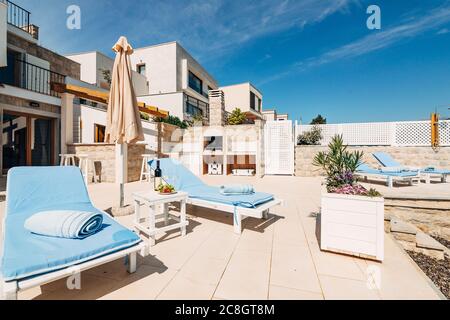 Transats en bois blanc dans la villa, près de la mer. Coussin bleu doux. La cour de la villa avec meubles de plage, coin barbecue, bar et Banque D'Images