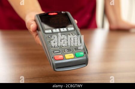 Le caissier propose un terminal de PDV pour le paiement par carte de crédit. Services bancaires, achats et paiement sans contact avec technologie NFC. Banque D'Images