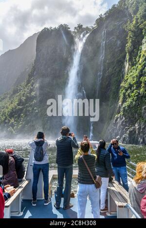 Touristes photographiant les chutes de Stirling depuis le pont d'un bateau de croisière, Milford Sound, Parc national Fiordland, South Island, Nouvelle-Zélande Banque D'Images