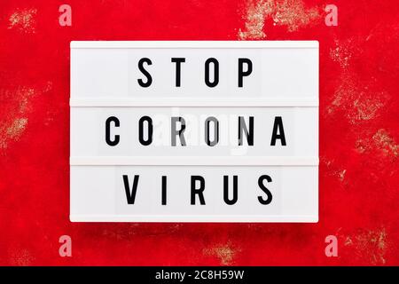 ARRÊTER LE VIRUS CORONA écrit dans une boîte lumineuse sur fond rouge. Concept de soins de santé et de médecine. Vue de dessus. Concept de quarantaine. Banque D'Images