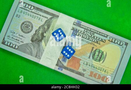 Deux dés sur des billets de cent dollars avec un fond vert Banque D'Images