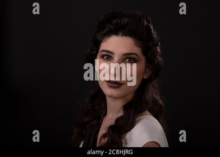 Portrait en gros plan d'une femme archer en robe blanche sur fond noir. La déesse grecque Artemis. Prise de vue en studio. Maquillage professionnel et coiffure f Banque D'Images