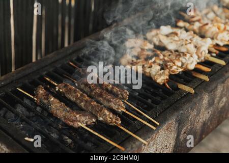 Vue rapprochée sur le gril de viande de poulet, Kebabs et saucisses sur le long barbecue rectangulaire avec fumée à l'extérieur de la rue. Barbecue d'été. BB Banque D'Images