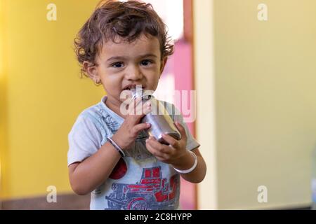 Un petit enfant qui boit du lait dans une bouteille de l'intérieur de la maison, portrait d'un enfant à l'intérieur Banque D'Images