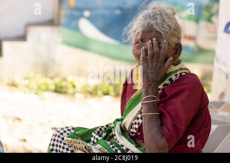 Chennai - Tamilnadu Inde. 24 juillet 2020. Une vieille dame assise avec ses mains sur sa bouche, portrait de femme à l'extérieur Banque D'Images