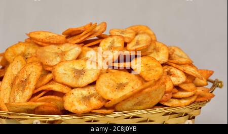 Chips de banane, tranches de pomme de terre se transformant en chips isolées, gaufrettes de kela croustillantes, salées, masala (gaufrettes), tomates, namekeen, chips sur un bol doré. Banque D'Images