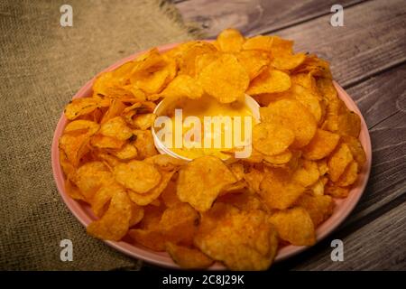 Croustilles sur un plateau rond et une casserole avec sauce au fromage. Gros plan Banque D'Images