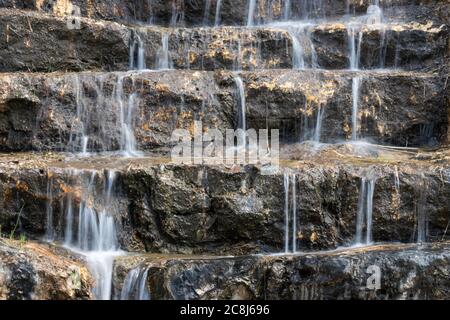 L'eau tombe dans plusieurs petites cascades sur des marches rocheuses, dans une photo à longue exposition. Banque D'Images