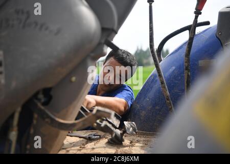 Changsha, province chinoise du Hunan. 21 juillet 2020. Tang Liehui fixe un tracteur dans un champ situé dans le village de Dongcheng, dans la ville de Yiyang, dans la province de Hunan, au centre de la Chine, le 21 juillet 2020. Ces derniers jours, les agriculteurs de Yiyang ont été occupés à récolter du riz de début de saison et à transplanter du riz tardif. Crédit: Xue Yuge/Xinhua/Alay Live News Banque D'Images