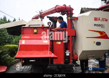 Changsha, province chinoise du Hunan. 21 juillet 2020. Tang Liehui fixe un reaper dans un champ du village de Tongxing de Yiyang City, dans la province de Hunan, au centre de la Chine, le 21 juillet 2020. Ces derniers jours, les agriculteurs de Yiyang ont été occupés à récolter du riz de début de saison et à transplanter du riz tardif. Crédit: Xue Yuge/Xinhua/Alay Live News Banque D'Images