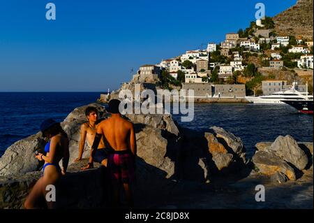 Hydra, Grèce. 24 juillet 2020. Les jeunes en maillots de bain se trouvent à l'entrée du port. L'île d'Hydra, qui couvre près de 50 kilomètres carrés, est à 65 kilomètres au sud-ouest d'Athènes. Les voitures, les enseignes au néon et les chaises en plastique sont interdites sur l'île. Credit: Angelos Tzortzinis/dpa/Alay Live News Banque D'Images