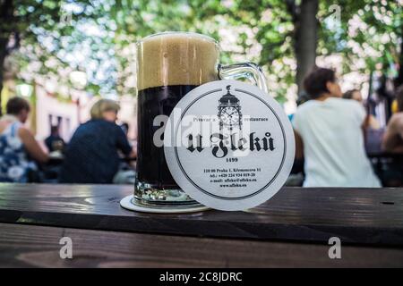 Prague, République Tchèque - juillet 10 2020 : verre avec bière foncée dans le jardin U Fleku avec dessous de verre et logo sur une table. Banque D'Images