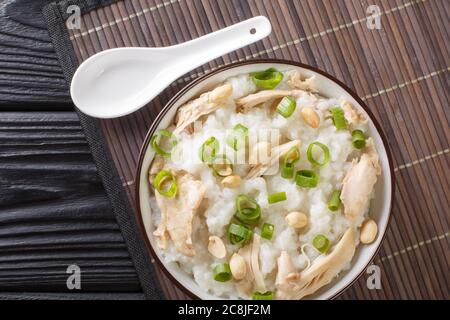 Faites un tour de bouillie de riz légèrement salé avec du poulet, des arachides et des oignons verts dans un bol sur la table. Vue horizontale du dessus Banque D'Images
