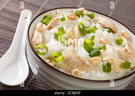 Cuisine chinoise, le congee a fait cuire du riz bouillante avec beaucoup d'eau à feu doux avec l'ajout de poulet, d'arachides et d'oignons verts dans un bol Banque D'Images