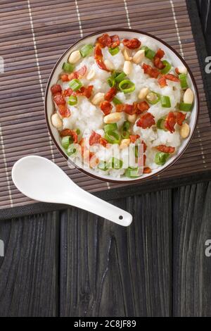 Cuisine chinoise, le congee a fait cuire du riz bouillante avec beaucoup d'eau à feu doux avec l'ajout de bacon, d'arachides et d'oignons verts dans un bol Banque D'Images