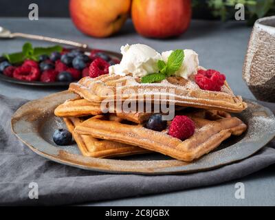 Gaufres belges avec framboises, sirop de chocolat. Petit déjeuner avec thé sur fond sombre, vue latérale, gros plan Banque D'Images