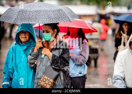 Une femme a été vue portant un masque facial et portant un parapluie pendant une journée pluvieux d'été.les gens portent des masques protecteurs sur la rue commerçante de Rotterdam un jour pluvieux en été, car la demande de masques augmente en raison de nouveaux cas d'infection à coronavirus. Mesures coronavirus état obligatoire masques dans magasins, cinémas et lieux publics et distance sociale de 1.5 mètres. Banque D'Images