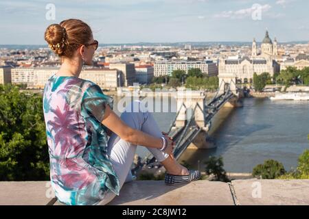 Jeune femme caucasienne à tête rouge, 20s, assise au panorama de Budapest, Hongrie Banque D'Images