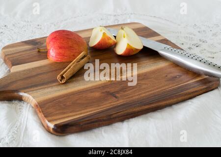 Quartiers de pomme avec bâton de cannelle et cannelle moulue sur planche à découper en bois Banque D'Images