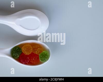 Sucrée mélange de bonbons de couleur dans une cuillère blanche sur fond blanc, isolé, avec espace de copie Banque D'Images