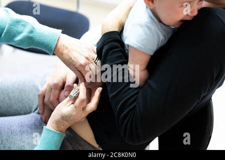 Du vrai bébé soit vacciné avec une seringue dans la cuisse par un médecin pédiatre pour éviter la propagation des maladies. Banque D'Images