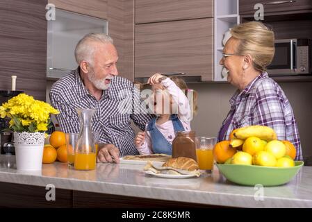 Petite fille faisant des crêpes avec ses grands-parents Banque D'Images