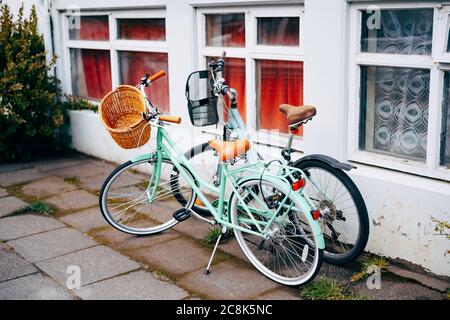 Deux vélos avec paniers d'épicerie par une vieille maison avec de grandes fenêtres. Banque D'Images