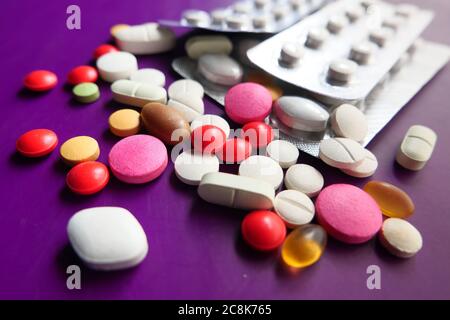 gros plan de pilules colorées qui se répandent sur fond violet Banque D'Images