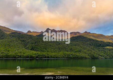 Forêts et montagnes entourant le lac Mavora Nord au coucher du soleil par une journée nuageux. Banque D'Images