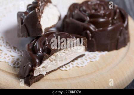 Un guimauve au chocolat en forme de rose repose sur une serviette blanche. Un guimauve est coupé en deux, une coupe est visible. Gros plan. Banque D'Images