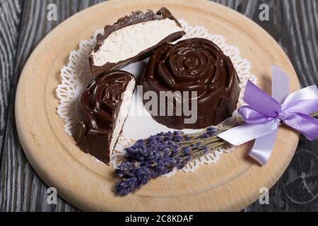 Un zephyr au chocolat fait en forme de rose repose sur une serviette blanche. Un zephyr est coupé en deux, une coupe est visible. Près d'un bouquet de lavande. Banque D'Images