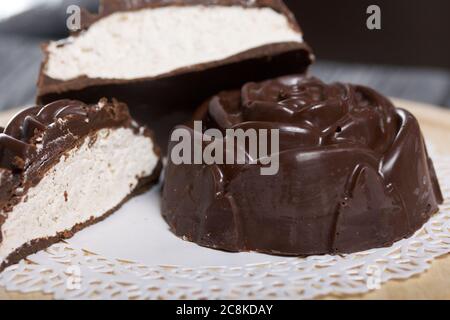 Un guimauve au chocolat en forme de rose repose sur une serviette blanche. Un guimauve est coupé en deux, une coupe est visible. Gros plan. Banque D'Images