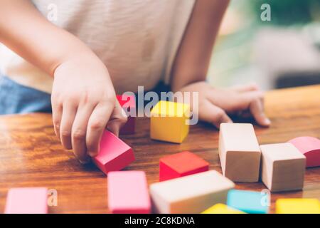 Gros plan main de garçon jouant en bois bloc jouet sur la table pour la création et le développement avec plaisir, enfant heureux apprendre compétence pour l'activité puzzle et creativ Banque D'Images