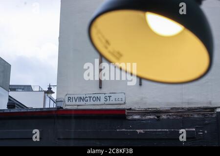 Signal de rue de Rivington à Londres sur un mur blanc de bâtiment vue d'une barre de fenêtre avec une lampe floue allumée Banque D'Images