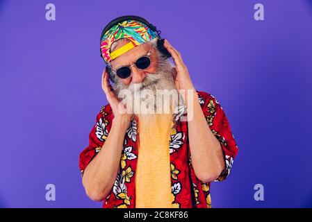 Homme âgé de 60 ans, avec un look excentrique, s'amusant, portrait sur fond coloré, concepts sur les jeunes seniors et mode de vie Banque D'Images