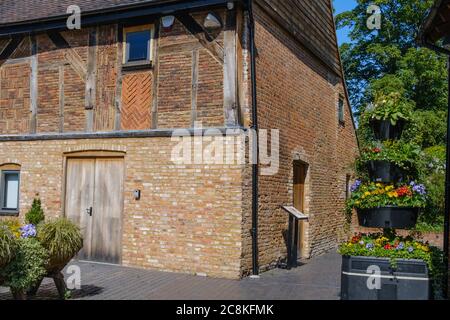 The stables, bâtiment du XVIIe siècle à ossature de bois, jardinières en bois, fleurs et feuillage pourpres et jaunes, Eastcote House Gardens, Eastcote, Londres. Banque D'Images