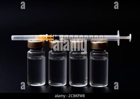 Vaccins, toxine botulinique et ampoules d'insuline concept thème avec des flacons en verre avec liquide clair à côté d'une seringue et une aiguille hypodermique isolée sur b Banque D'Images