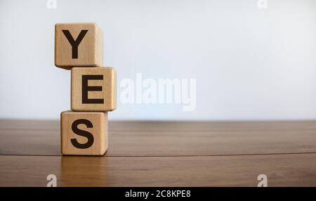 Cubes de bois avec le mot « oui » sur une table en bois, beau fond blanc, espace de copie. Concept d'entreprise. Banque D'Images