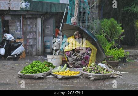 Beawar, Rajasthan, Inde, 24 juillet 2020: Vendeur vendant des légumes le long d'une route prendre refuge sous parapluie pendant la forte pluie à Beawar. Crédit : Sumit Saraswat/Alay Live News Banque D'Images